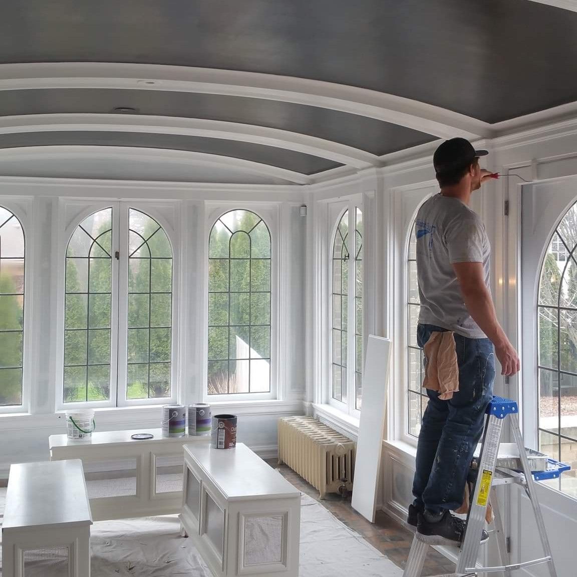 Trim being painted in a sunroom with arched windows